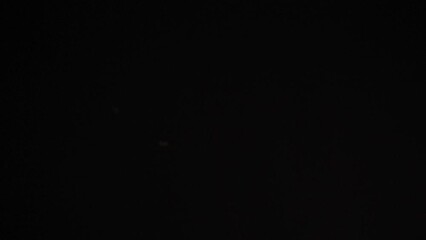 View of raspberries falling on black background