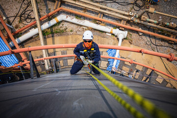 Naklejka premium Focus top view male worker down height tank roof rope access safety inspection of thickness storage tank .