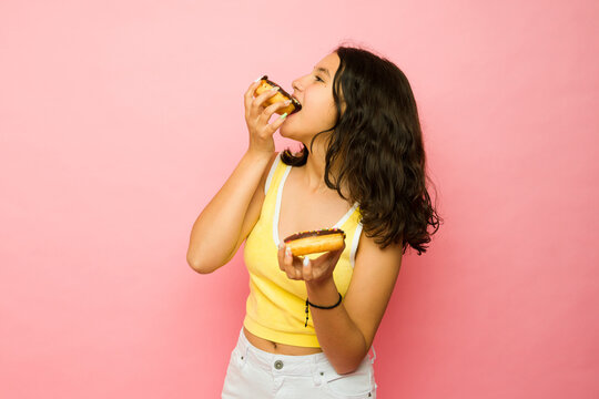 Hungry teen girl eating chocolate donuts