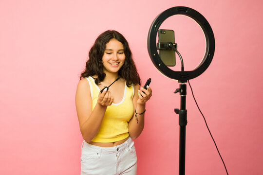 Excited teen influencer filming a makeup video tutorial