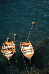 Vertical shot of two wooden boats moored on a calm rocky coast in Vernazza, Cinque Terre, Italy