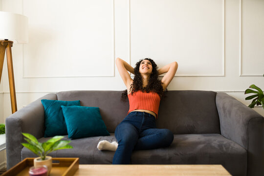 Happy relaxed young woman enjoying resting on her sofa