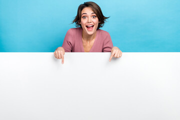 Photo of young crazy woman indicating fingers empty space banner crazy proposition product placement isolated on blue color background - obrazy, fototapety, plakaty