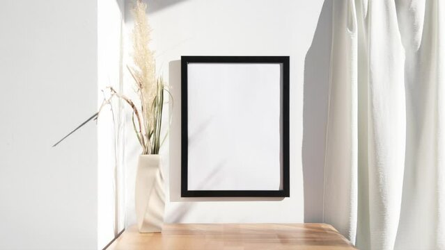 Black photo frame video mockup on wall with beige vase on wooden table