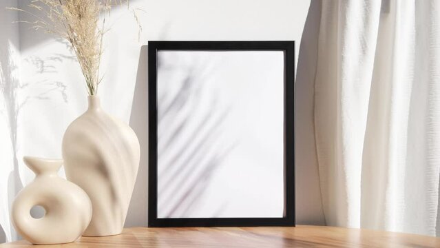 Black photo frame video mockup with beige vases on wooden round table