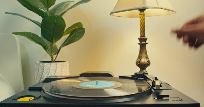 Vinyl Player on the Table With an Old Lamp, Listen to Music on Old Vinyl Records. Vintage Vinyl Record Spinning on an Old Turntable. Man's Hand Removes the Needle's Head From the Plate. 