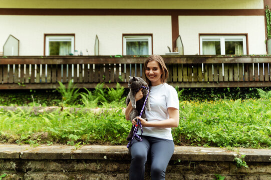 happy cat owner. girl sits with a cat on the background of the building and nature. cat with leash and carrier. walk with the cat