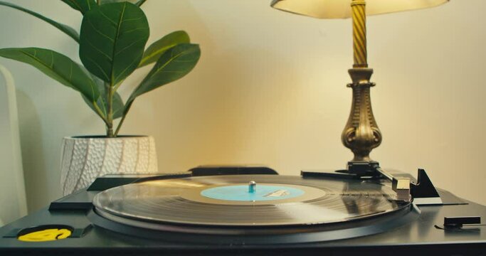 Vinyl Player on the Table With an Old Lamp, Listen to Music on Old Vinyl Records. Vintage Vinyl Record Spinning on an Old Turntable. Man's Hand Removes the Needle's Head From the Plate. 