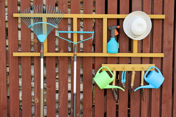 The set of different tools and equipment for gardening at wooden wall of shed with birch firewood. 