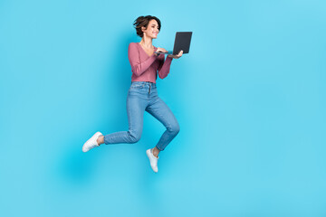 Full length body photo of young careless girl jumping hold netbook freelancer remote job programmer isolated on blue color background