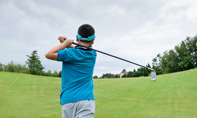 Little boy playing golf on a field