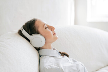 Relieves stress listening to calm music playlist audiobook woman in wireless headphones in the app, comfortably resting a break at work.