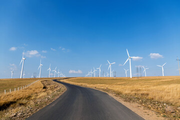 Empty asphalt highway road surrounded by fields with windmills