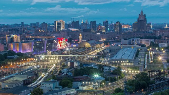 Panoramic top view to Kiev Railway Station night to day transition timelapse and modern city in Moscow, Russia. Aerial rooftop view with trains and rail tracks. Illuminated buildings from above