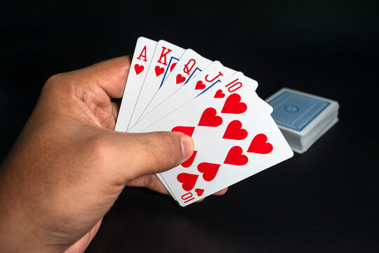 man hand holding royal flush of playing cards on black background