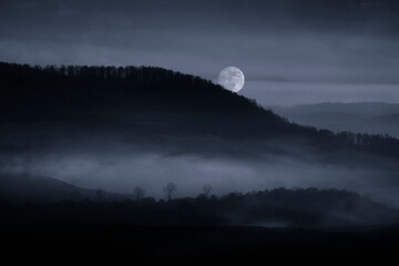 full moon rising over misty hills at night, dark landscape