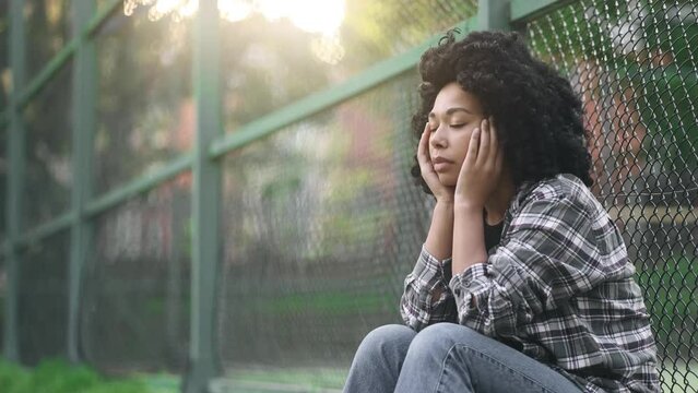 Portrait of sad young African American girl suffering from depression anxiety loneliness or mental problem while someone offers her helping hand outdoors Faith and support concept