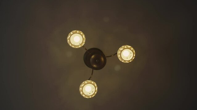 Ceiling lamp turning on in semi-dark premise of apartment. Light bulb lit up last. Electrical and artificial lighting concept low angle shot