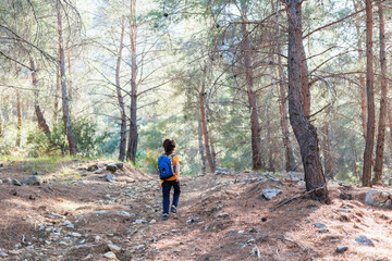 Obraz premium Traveling child. a tourist with a backpack goes along a mountain road. adventure holidays with children.