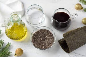 Ingredients for vegan black caviar: chia seeds, soy sauce, linseed oil, water and nori on a light blue background, top view.