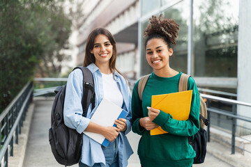 Two University Student girls looking at camera smiling outdoors at the college campus . education portrait