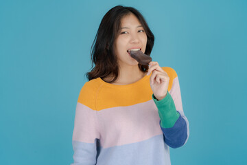 Beautiful young woman smiling happily while holding ice cream in her hand