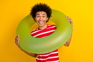 Photo of funky cheerful man dressed red t-shirt holding inflatable circle isolated yellow color...