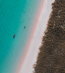 Woman walking and enjoying empty paradise tropical beach. Nobody around. Aerial view of Padar island Pink Beach. Vertical photo.