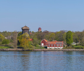 Fototapeta na wymiar Old lint oil mill, brick tower and old mansion houses at the water front in the island Djurgården at the bay Saltsjön, a tranquil sunny summer day in Stockholm