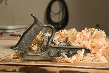 Combination plane before pile of pine shavings. Woodworking by hand.