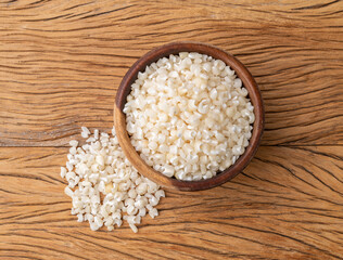Dried canjica, hominy or white corn on a bowl over wooden table