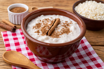 Canjica or munguza, typical brazilian white corn sweet cream with cinnamon over wooden table