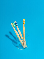 multiple bamboo toothbrush in a cup on blue background