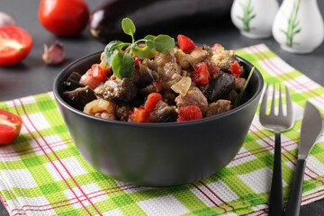 Meat stew with eggplant and tomatoes served in dark bowl on a gray background, Close up