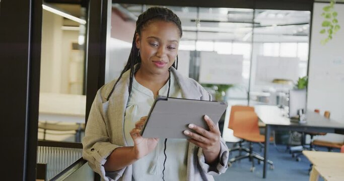 Happy african american casual businesswoman using tablet standing in office, slow motion