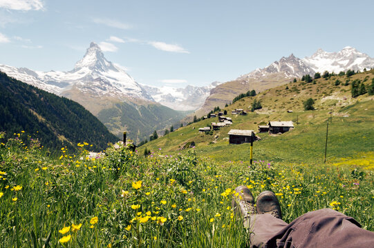 Showing hiking boots and legs, having a break during a hike in the Alps, Matterhorn at the background