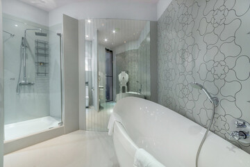 Stylish bathroom design with mirrored wall. The bath has an elegant shape, a shower cabin with...