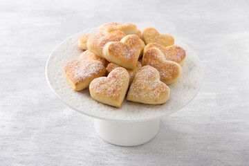 Soft curd cookies sprinkled with powdered sugar on a white plate on a light gray background. Delicious homemade cookies - 605345496