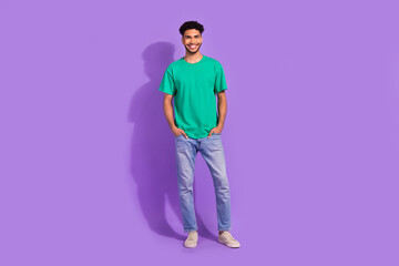 Fototapeta na wymiar Full body photo of young cheerful guy wear green t-shirt denim jeans stylish sneakers posing hm sale isolated on purple color background