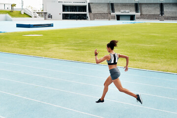 Woman, fitness and running of athlete on track for exercise, cardio training or workout outdoors....