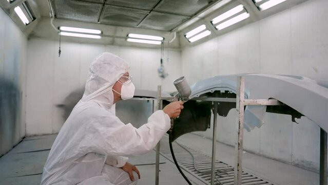 Car painters wear PPE over their heads and goggles over their mouths. standing in spray booth Painting a car that is not airy The mechanic uses a paint sprayer gradually. spray paint on car surface