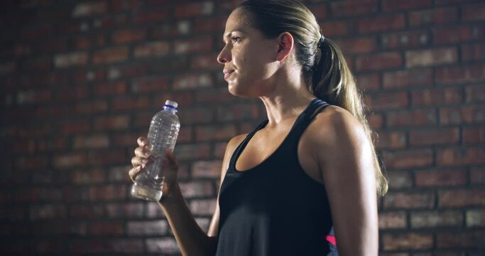Relax, fitness or girl drinking water in training, workout or exercise to hydrate her body in gym studio. Fatigue, wellness or tired woman with a bottle for healthy liquid hydration on resting break