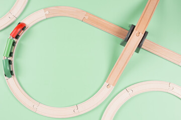 Baby kid toys background. Toy train and wooden rails on light green background. Top view, copy space