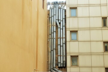 Interlacing of numerous ventilation pipes on the wall between buildings