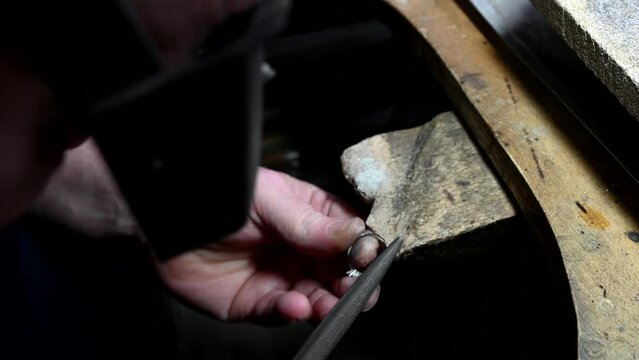 Gold wedding ring craft by goldsmith, isolated. Macro video. Craft jewelry making with professional tools. Process of ring polishing making handmade. 4k raw slow motion video