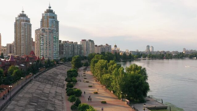 Aerial drone view of city river embankment. Urban cityscape with walking people.