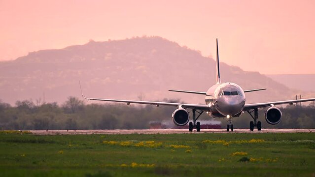 Huge airplane jet maneuvering after landing at international airport landing zone at beautiful sunset clouds sky and big mountings. 4k super slow motion raw video 120 fps