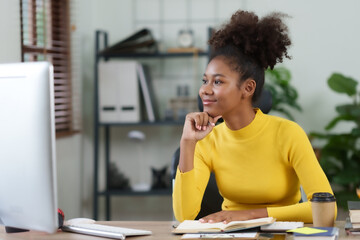 Beautiful young black woman using laptop computer at home. Young woman curly hair working on laptop and take note at home.