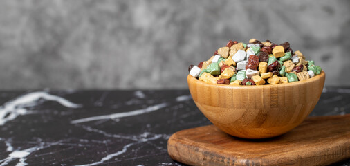 Colorful chocolate candy stones. Stone chocolate dragee in wooden bowl on dark background. Small multi-colored candies. Copy space. Empty space for text