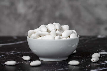 Almond candy. Sugar coated almond candy in ceramic bowl on dark background. Small multi-colored candies